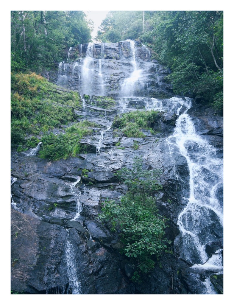 photo of Amicalola Falls in Georgia, where many thin streams of water fall over multiple cascades over dark rocks where lush green bushes cling