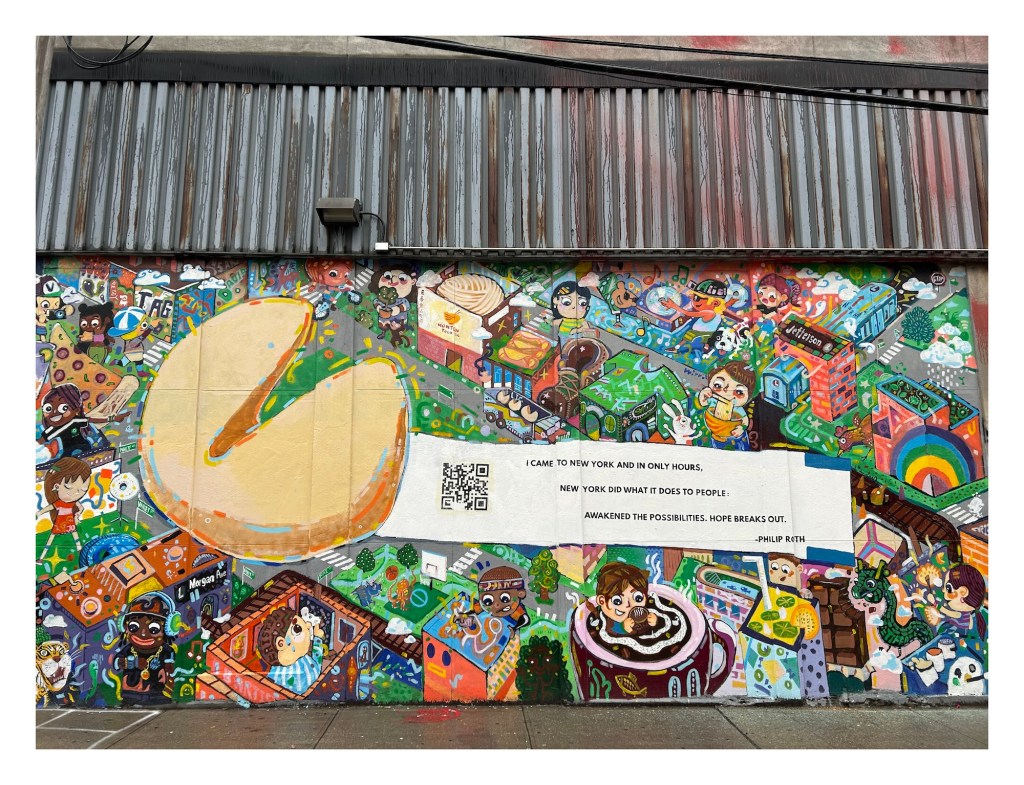 painted mural with a large fortune cookie with a Philip Roth poem printed on its paper slip; the background is a painted cityscap with exaggerated cartoon people enjoying city life